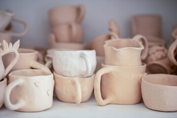 Close-up portrait of a smiling young girl in an apron in a pottery studio. Joyful child surrounded by unfired clay ceramics, emphasizing creative learning and hands-on craft.