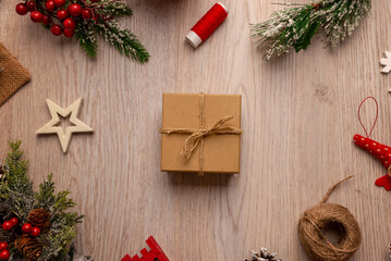 Wrapped gift box with twine on wooden table surrounded by festive elements, ideal for packaging concepts, small business branding and handmade product presentation