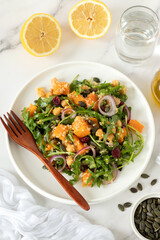 Roasted pumpkin chickpea arugula quinoa salad in a plate with fork. Top view. Healthy vegan thanksgiving meal.