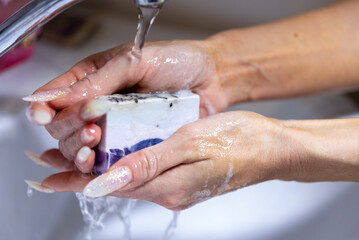 Woman washing hands with foaming soap on white background, closeup.