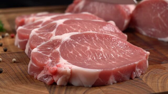 Trozos de carne cruda sobre mesa, manos femeninas cortando de cerca.