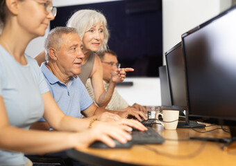 Obraz premium Curious mature man engaged in IT training with help of teacher in computer courses