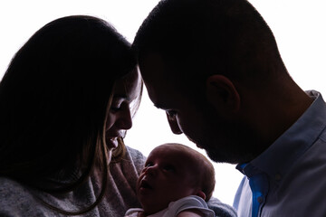 Parents and newborn baby silhouette bonding together