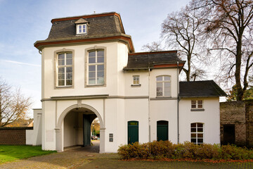The historic white baroque gatehouse (Prälaturflügel) of the former Brauweiler Abbey near Cologne, Germany, featuring a central archway and slate mansard roof