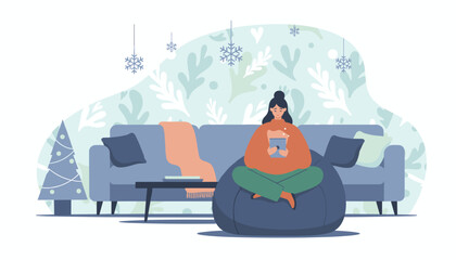 Woman relaxing on beanbag with tablet in cozy festive winter living room