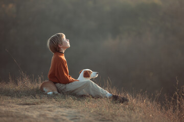 child and dog sit together on grassy hill enjoying soothing sounds of music