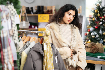 Woman tries on a fashionable fur coat in a fashionable clothing store