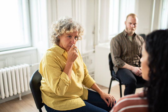 Senior woman emotional during group therapy in bright room