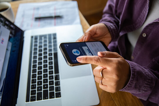 Focused young adult using mobile banking app at home desk