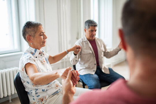 Senior and mature adults holding hands in a calm support group indoors