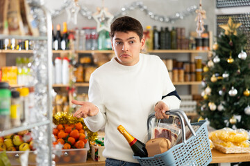 Young man shopper buying food in grocery store decorated for christmas