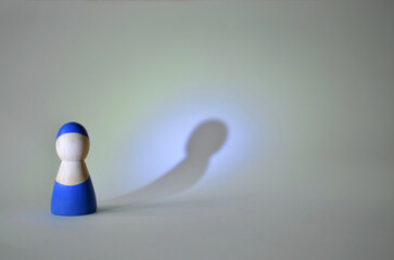 Blue wooden figurine casting long shadow on wall