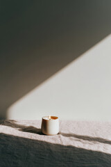 delicate candle stands gracefully on textured linen tablecloth offering cozy ambiance