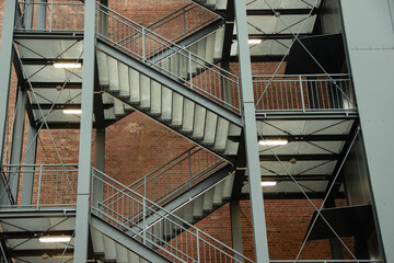 Industrial staircase design featuring metal steps and railings, showcasing a modern architectural structure with a backdrop of exposed brick walls and ambient lighting