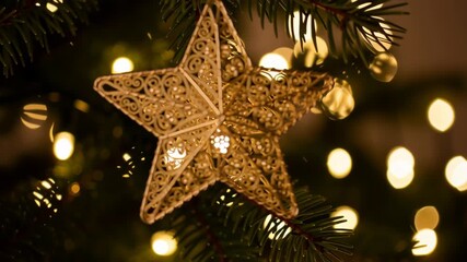Golden filigree star ornament hanging fir branch with warm bokeh lights creating cozy christmas work mood and holiday decoration evening gold light filigree christmas fir bokeh ornament gold - Powered by Adobe