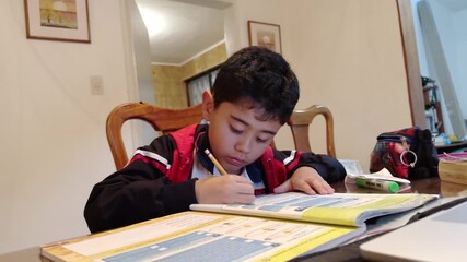 Young Latino Boy Concentrating on Homework/School Work at Home Desk (Close-Up)