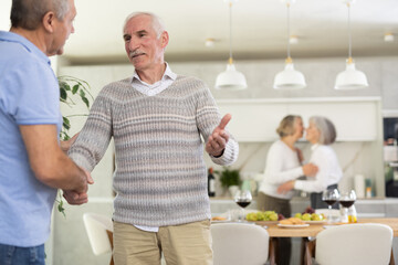 Two men smiled and greeted each other with a firm handshake before taking their seats at the...