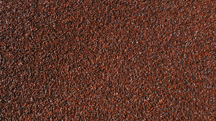Close-up of abrasive sandpaper texture in a maroon color. Detailed background of a rough granular material for construction and renovation