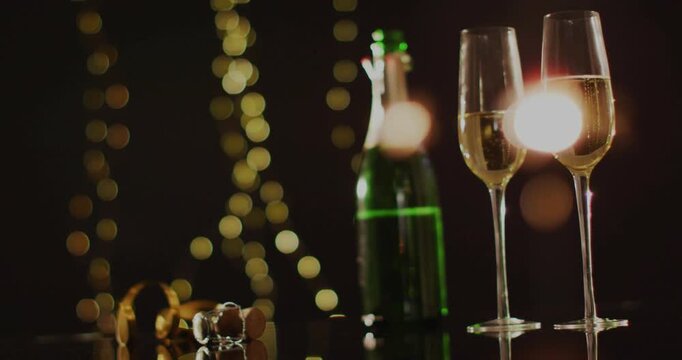 Champagne bottle and two flutes shifting into focus after bright flare, emphasizing festive mood