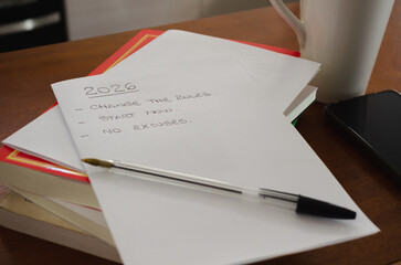 Paper sheets on a books stack  with a list of goals for 2026 year. Motivational action plan. Learning at home concept.