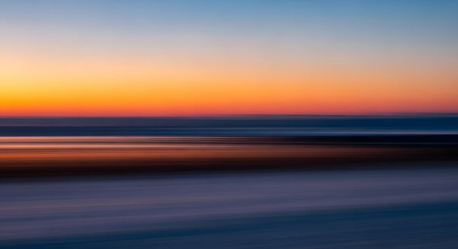 Abstract sunset scene, a calming blend of orange, blue, and violet, captured through intentional camera movement, creating a sense of peace and fluid motion and evoking feelings of tranquility and