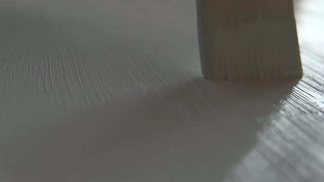 Close up of an artist priming canvas with white ground, preparation for painting. Selective focus