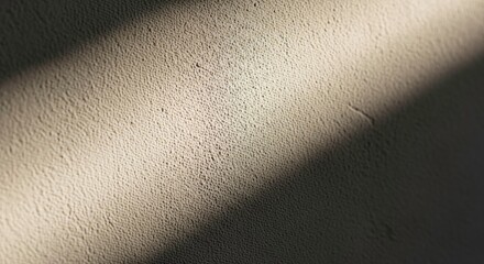 Closeup of a textured wall with a diagonal beam of sunlight creating a shadow