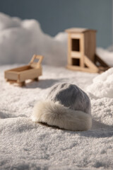 cozy winter scene featuring warm hat resting on snowy ground next to playful toy sleds