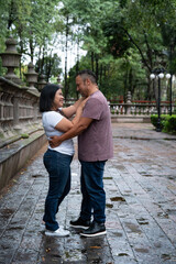 Fototapeta premium Smiling couple sharing tender moment in city park after rain