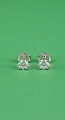 A pair of elegant silver earrings with large, sparkling gemstones displayed on a vibrant green background for a luxurious jewelry presentation