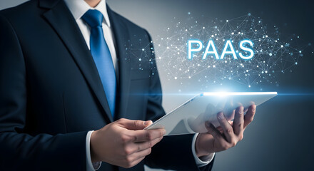 Businessman in a suit holds a tablet displaying "PAAS" with a network graphic representing platform as a service technology for cloud computing and business solutions in the digital age