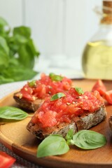 Tasty bruschettas with tomatoes and basil on table, closeup