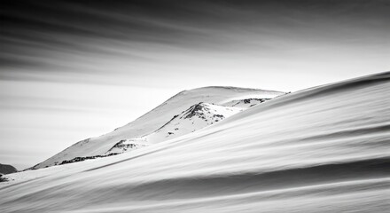 Black and white shot of snow-covered mountains with windswept drifts and overcast sky