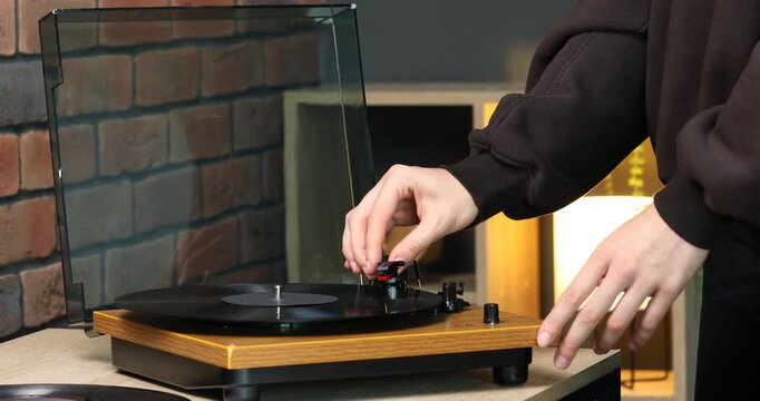 Woman turning record player with vinyl disk on at home, closeup