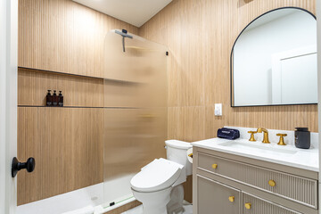 Modern bathroom with wood-panel walls, glass shower and gold fixtures