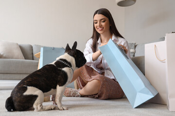 Young woman with shopping bag and her French bulldog at home