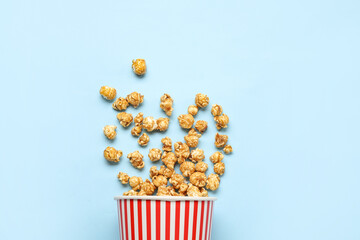 Bucket with tasty popcorn on blue background