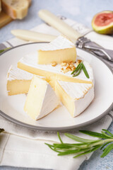 Plate with pieces of tasty Camembert cheese on grey background