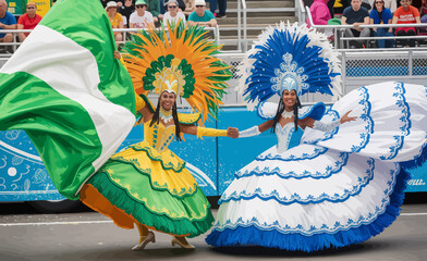 Two vibrant dancers in elaborate costumes celebrate at a colorful parade