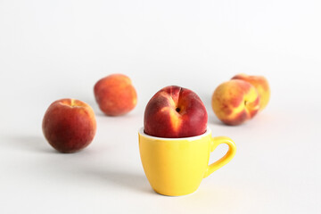 Cup with sweet peaches on white background