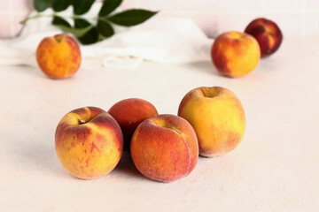 Sweet peaches and leaves on white table