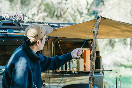 Male camper setting up a tent at a campsite in autumn and winter
