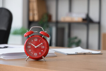 Red alarm clock on desk in office, closeup