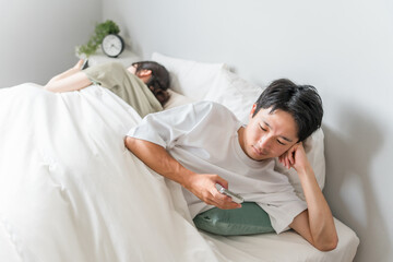 A couple in bed who are both addicted to smartphones and are not getting along