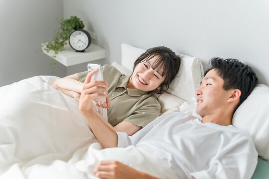 A couple watching videos on their smartphone in bed