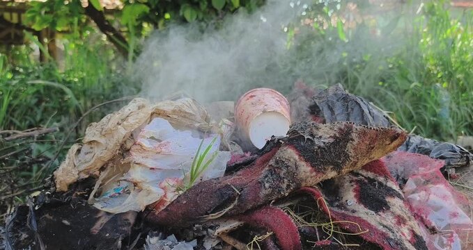 Outdoor garbage burning and white smoke rising. 