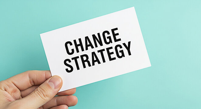 Hand holding a card with the words change strategy against a light blue background promoting business growth and innovative solutions