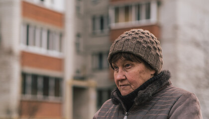 Elderly woman reflecting thoughtfully in urban park during a cool afternoon in early autumn