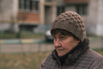 Elderly woman reflecting thoughtfully in urban park during a cool afternoon in early autumn