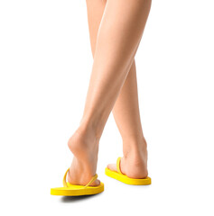 Female legs in yellow flip-flops on white background, back view